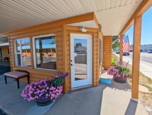 a wooden house with flowers in front of it at Teton Court Motel in Pinedale