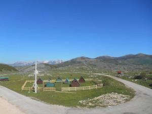 a group of huts in a field next to a road at Etno selo - Guest House Etno Village - TRSA in Pluzine