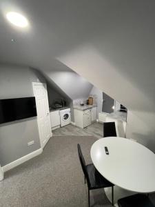 Habitación con mesa blanca, sillas y cocina. en Luton Short Term Lets - Cardiff Road en Luton