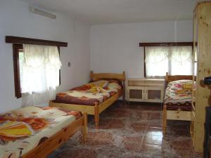 a bedroom with two beds and a desk and two windows at Kuma Lissa Guest House in Kozhari