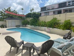 a swimming pool with two chairs and a table and chairsitures at #6 Ferguson Rd - Townhouse in Nassau