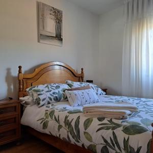 a bed with a wooden headboard and pillows on it at Casa Reibon in Santiago de Compostela