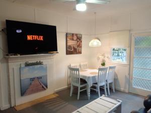 a dining room with a table and a tv above a fireplace at The Boathouse a 3 Bedroom House in Narooma