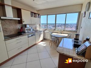une cuisine avec des armoires blanches, une table et une fenêtre dans l'établissement Bel appartement avec vue splendide sur toute la ville de Colmar - Parking gratuit, à Colmar 20 autres photos