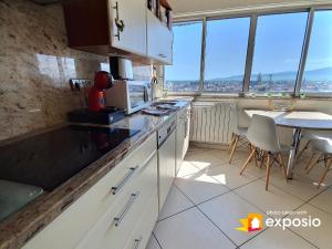 une cuisine avec des armoires blanches et une table avec des chaises dans l'établissement Bel appartement avec vue splendide sur toute la ville de Colmar - Parking gratuit, à Colmar