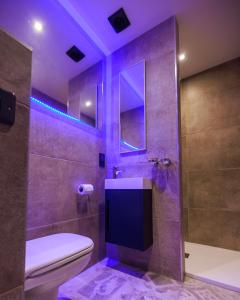 a bathroom with a toilet and a shower with purple lighting at Vancouver Studios in London