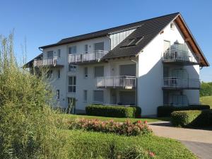 un edificio de apartamentos blanco con balcones y arbustos en Serviced Apartments Hertingen, en Bad Bellingen
