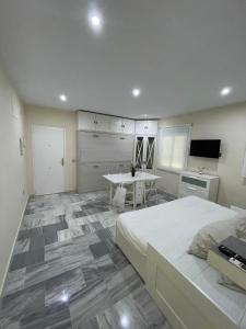 ein Schlafzimmer mit einem Bett und einem Tisch sowie eine Küche in der Unterkunft Apartamento en calle Rocio-Triana in Sevilla