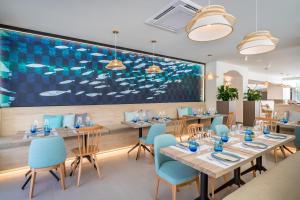 a dining room with tables and blue chairs at Occidental Puerto Banús in Marbella