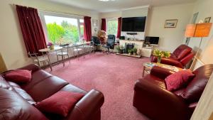 a living room with leather furniture and a woman sitting in a chair at Old Captain Guest House in Portree
