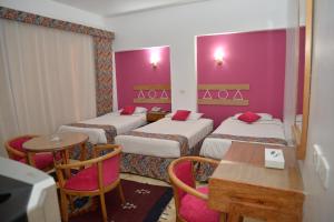 アスワンにあるマルハバ パレス ホテルのベッド3台、テーブル、椅子が備わるホテルルームです。