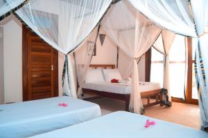 two beds in a room with white drapes at Kusini beach bungalows in Kizimkazi