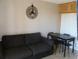 sala de estar con sofá y reloj en la pared en Risoul 1850 appartement 4 personnes proches pistes. en Risoul