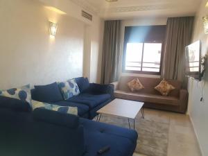 Una sala de estar con sofás azules y una mesa. en Central Aparts Av Prince Moulay Abdellah, en Marrakech