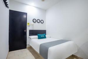 a bedroom with a bed with a blue pillow on it at Ayenda Hotel Alejandría in Montería