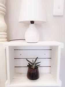 a white table with a lamp and a plant on it at Cooper Cottage in Howick