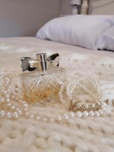 a glass perfume bottle and pearl necklace on a bed at Cooper Cottage in Howick