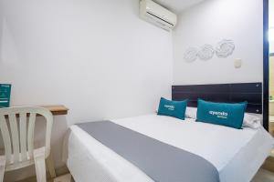 - une chambre avec un lit doté d'oreillers bleus et d'un bureau dans l'établissement Ayenda Hotel Alejandría, à Montería