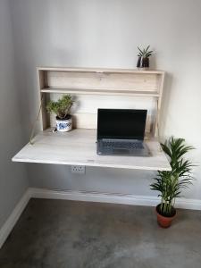 un ordenador portátil sentado en un escritorio con plantas en Cooper Cottage en Howick