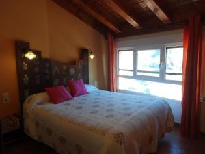 um quarto com uma cama com almofadas cor-de-rosa e uma janela em Spa y Casa Rural Rio Dulce em Aragosa