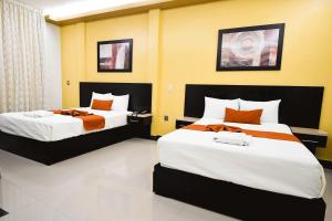um quarto com 2 camas com lençóis laranja e branco em Hotel los faroles em Ocozocuautla