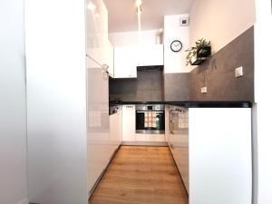 a kitchen with white cabinets and a wooden floor at Matejki Apartment ~ Self Check-In 24 ~ Parking in Wrocław
