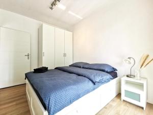 a white bedroom with a large bed with blue pillows at Matejki Apartment ~ Self Check-In 24 ~ Parking in Wrocław