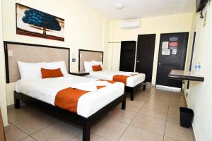 a hotel room with two beds and a desk at Hotel los faroles in Ocozocuautla