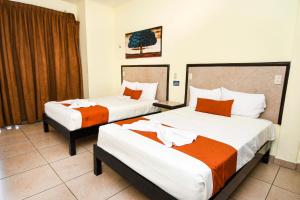 Cette chambre d'hôtel comprend 2 lits avec des draps orange et blancs. dans l'établissement Hotel los faroles, à Ocozocuautla