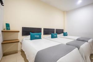 a row of beds in a room with blue pillows at Ayenda Hotel Alejandría in Montería