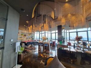 a restaurant with tables and chairs in a room with windows at Downtown Chic Condo Rooftop Pool #EN797 in Pattaya Central