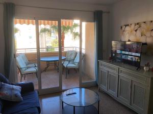 a living room with a tv and a table and chairs at Precioso apartamento en Urbanización junto al mar. in Alicante