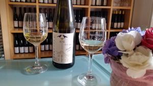 Dois copos de vinho branco e uma garrafa de vinho. em Weingut Raevenhof em Ayl