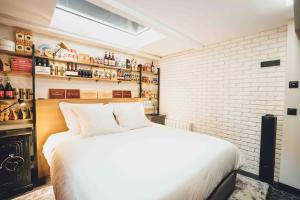 sypialnia z białym łóżkiem i ceglaną ścianą w obiekcie Parrot I Authentique appartement 4P w Paryżu