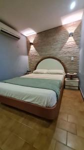 a bedroom with a large bed with a brick wall at Hotel El Arroyo in Caracas