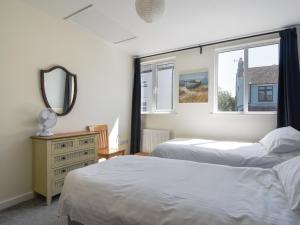 a bedroom with two beds and a mirror and windows at Bahari in Lyme Regis