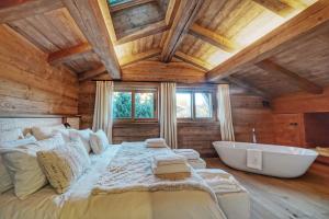 sypialnia z dużym łóżkiem i wanną w obiekcie Chalet Whymper avec piscine 150m téléphérique (neuf 2021) w mieście Megève