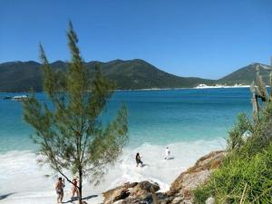 a group of people playing in the water on a beach at Edifício Royale flat 230 in Cabo Frio