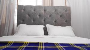 - un lit avec une tête de lit grise et 2 oreillers dans l'établissement Jameela House, 3 mins to Diani Beach, Spa, Laundry, Transport & Catering Available, à Ukunda