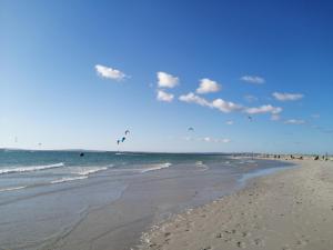 a beach with people flying kites in the ocean at Studio On Fairway in Langebaan