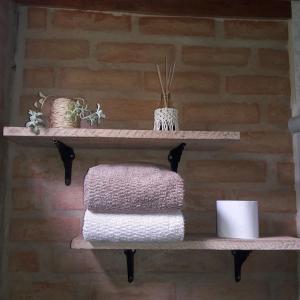 a shelf with three towels on a brick wall at Chalé Caminho da Montanha in Gonçalves