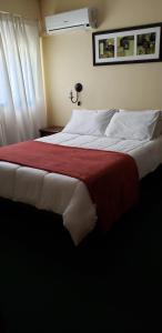 a bedroom with a large bed with a red blanket at Hotel Sol Colonia in Colonia del Sacramento