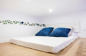 ein weißes Bett mit blauen Kissen in einem Zimmer in der Unterkunft Calle Amparo 86 Lujoso Dúplex con Jacuzzi en Lavapies especial parejas in Madrid + 27 Fotos