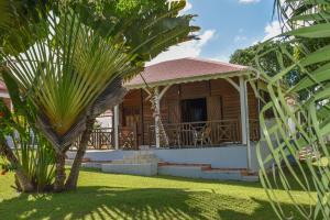 a wooden house with a porch in a yard at Gîtes du Domaine de la Canne à Sucre in Anse-Bertrand +5 photos