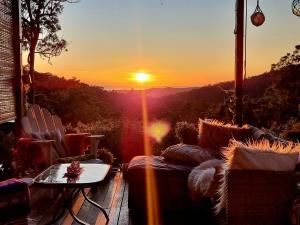 puesta de sol desde un balcón con sofás y mesa en The House of the Rising Sun, en Tallebudgera