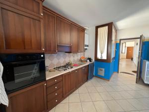 uma cozinha com armários de madeira e um forno com placa de fogão em ORIO Bergamo 24h AIRPORT TOP APPARTMENT VICINO ALL'AEROPORTO em Orio al Serio