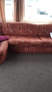 a brown couch sitting in front of a window at Shell’s Caravan in Lincolnshire