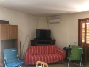 ein Wohnzimmer mit einem Sofa, einem Stuhl und einem TV in der Unterkunft Marchesana Terme - Holiday Home - Family in Terme Vigliatore