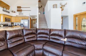 un sofá de cuero marrón en una sala de estar con una escalera en Woodland Chalet - Hot Tub Pool Table Private, en Sevierville