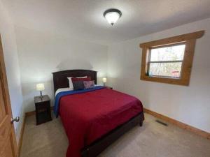 1 dormitorio con 1 cama con manta roja y ventana en Woodland Chalet - Hot Tub Pool Table Private, en Sevierville